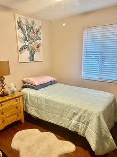 A bedroom with a bed, nightstand and window.